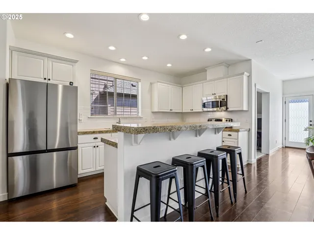 a kitchen with stainless steel appliances granite countertop a refrigerator a stove a sink a dining table and chairs