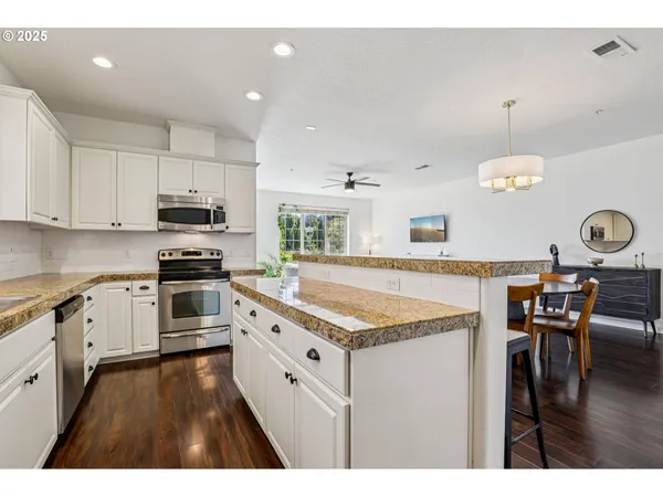 a kitchen with stainless steel appliances granite countertop a stove top oven a sink a dining table and chairs
