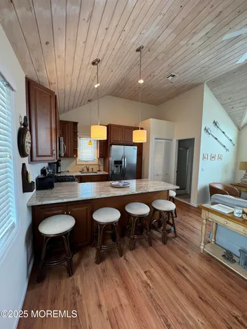 a open kitchen with stainless steel appliances granite countertop a stove a sink dishwasher a dining table and chairs with wooden floor