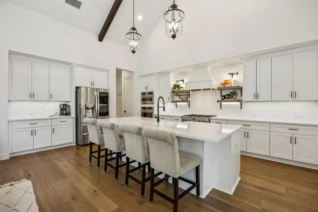 a kitchen with stainless steel appliances kitchen island granite countertop a table chairs sink and cabinets