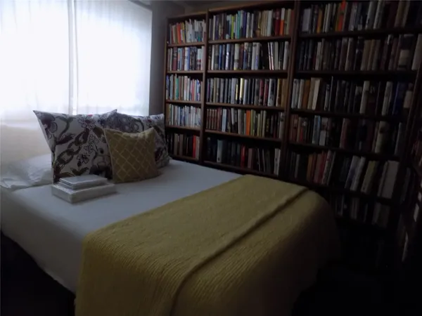 a bed sitting in a bedroom next to a book shelf