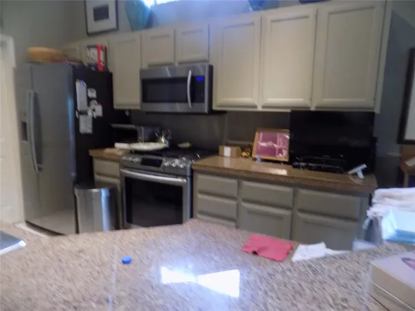 a kitchen with stainless steel appliances granite countertop a stove a sink and a microwave