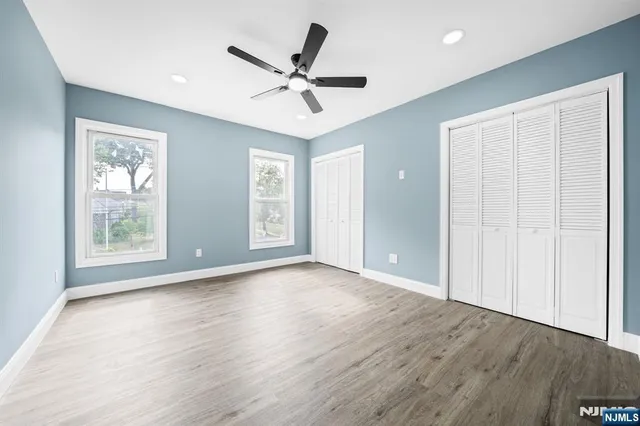 an empty room with wooden floor fan and windows
