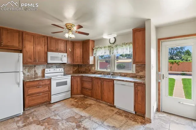 a kitchen with granite countertop a stove a sink and a refrigerator