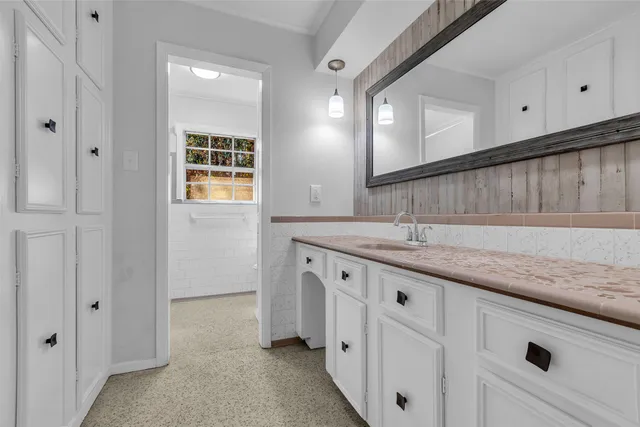 a spacious bathroom with a granite countertop sink and a mirror