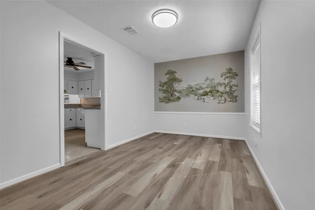 an empty room with wooden floor and windows