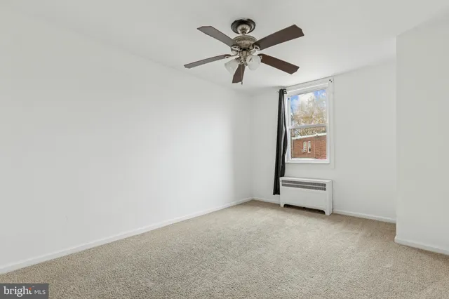 an empty room with a window and a fan