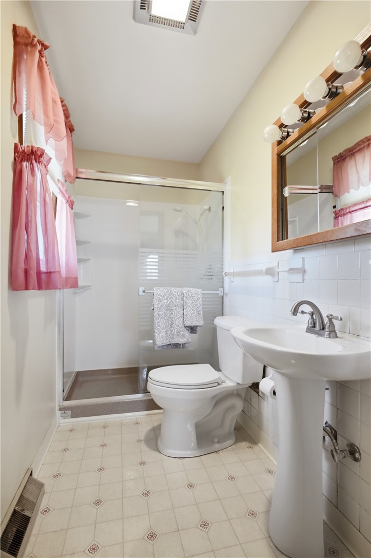 6718 Old Columbus Road South Vienna, OH 45369 - Photo 19 of 33 This bright bathroom features a convenient walk-in shower and classic pedestal sink.