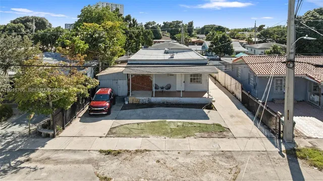a view of a white house with a small yard plants and large tree