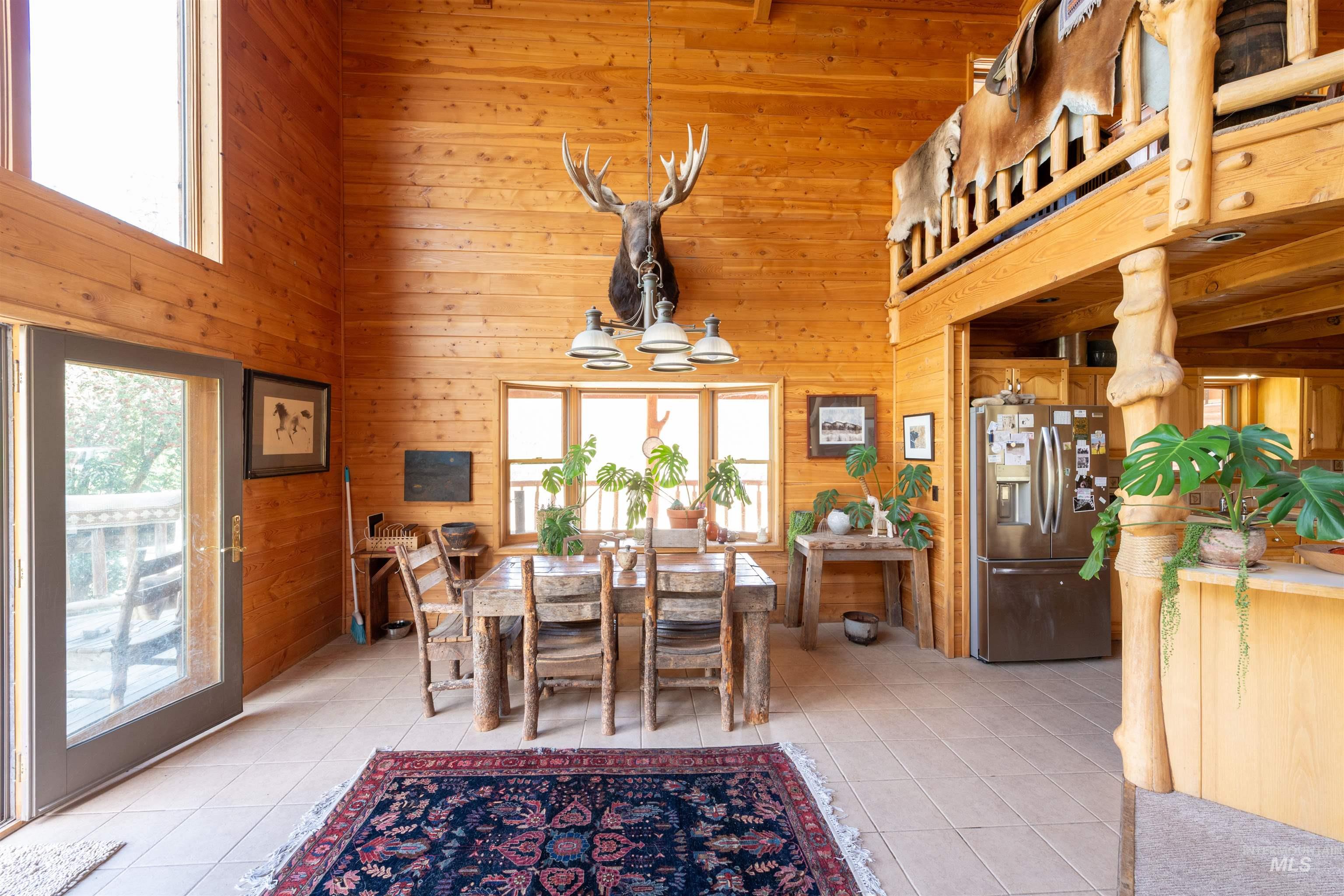 9885 Challis Creek Road Challis, ID 83226 - Photo 15 of 48 Dining area featuring light tile patterned floors, wooden walls, and a high ceiling