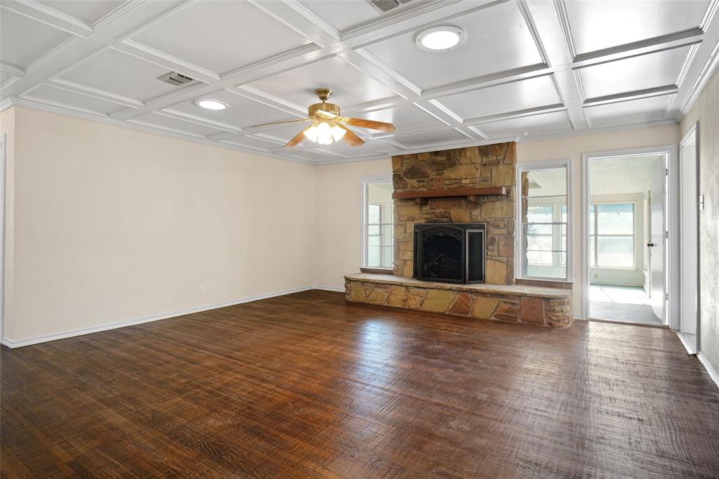 221 West 5th Street Springtown, TX 76082 - Photo 3 of 20 an empty room with wooden floor fireplace and chandelier fans