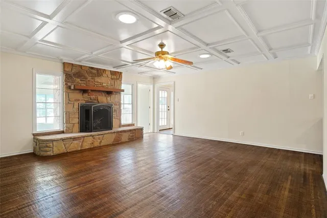 an empty room with wooden floor fireplace and a window