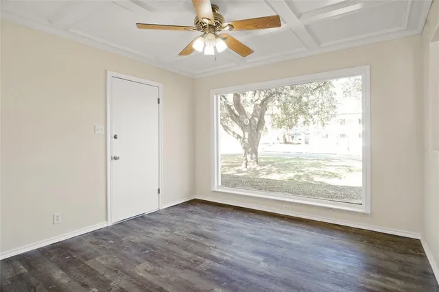 an empty room with wooden floor chandelier fan and windows