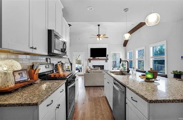 a kitchen with granite countertop a sink a stove a oven a dining table and chairs