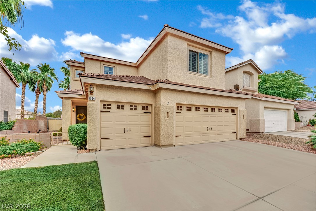 1724 Millstream Way Henderson, NV 89074 - Photo 3 of 60 A well-maintained stucco home offers ample parking with multiple garage bays and a broad driveway.