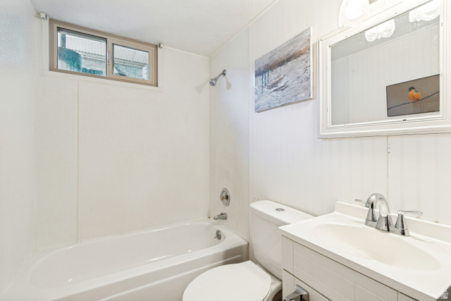 127 West 300 North Springville, UT 84663 - Photo 20 of 24 White bathroom featuring a bathtub with an integrated shower, a window with light-colored trim, a white vanity with an integrated sink, a chrome two-handle faucet, and vertical paneling on the wall