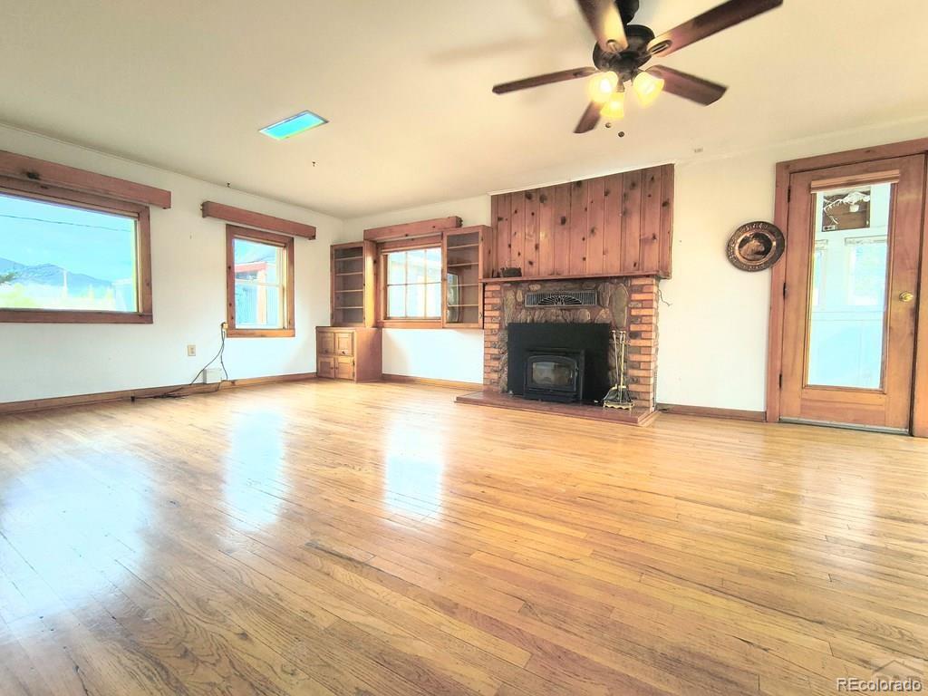 8180 Old San Isabel Road Rye, CO 81069 - Photo 7 of 35 an empty room with windows fireplace and wooden floor