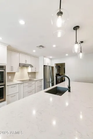 a kitchen with kitchen island a sink stainless steel appliances and cabinets