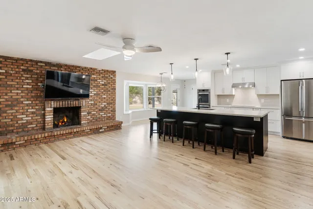 a large kitchen with stainless steel appliances kitchen island granite countertop a large stove a sink dishwasher and white cabinets with wooden floor