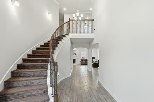 24714 Longwood Forest Drive Spring, TX 77373 - Photo 5 of 21 This photo showcases a spacious, elegant entryway with a curved staircase featuring dark wood steps and a decorative railing. The area is well-lit with modern fixtures and has light-colored walls and wood flooring, creating a welcoming atmosphere.