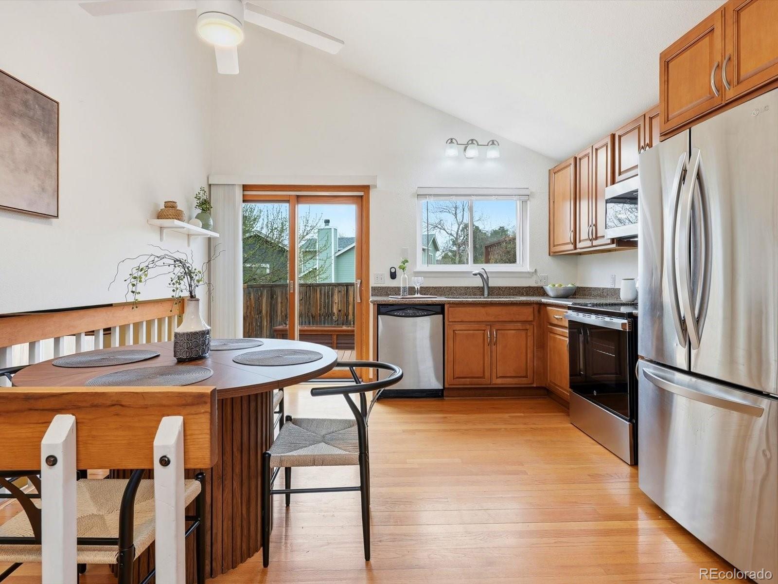 765 Stowe Street Highlands Ranch, CO 80126 - Photo 11 of 43 a kitchen with stainless steel appliances granite countertop a refrigerator a sink dishwasher a stove with white cabinets and wooden floor