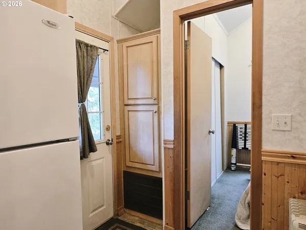 a view of hallway with a refrigerator and a window