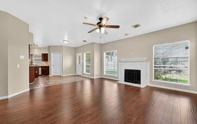 a view of an empty room with a kitchen and wooden floor