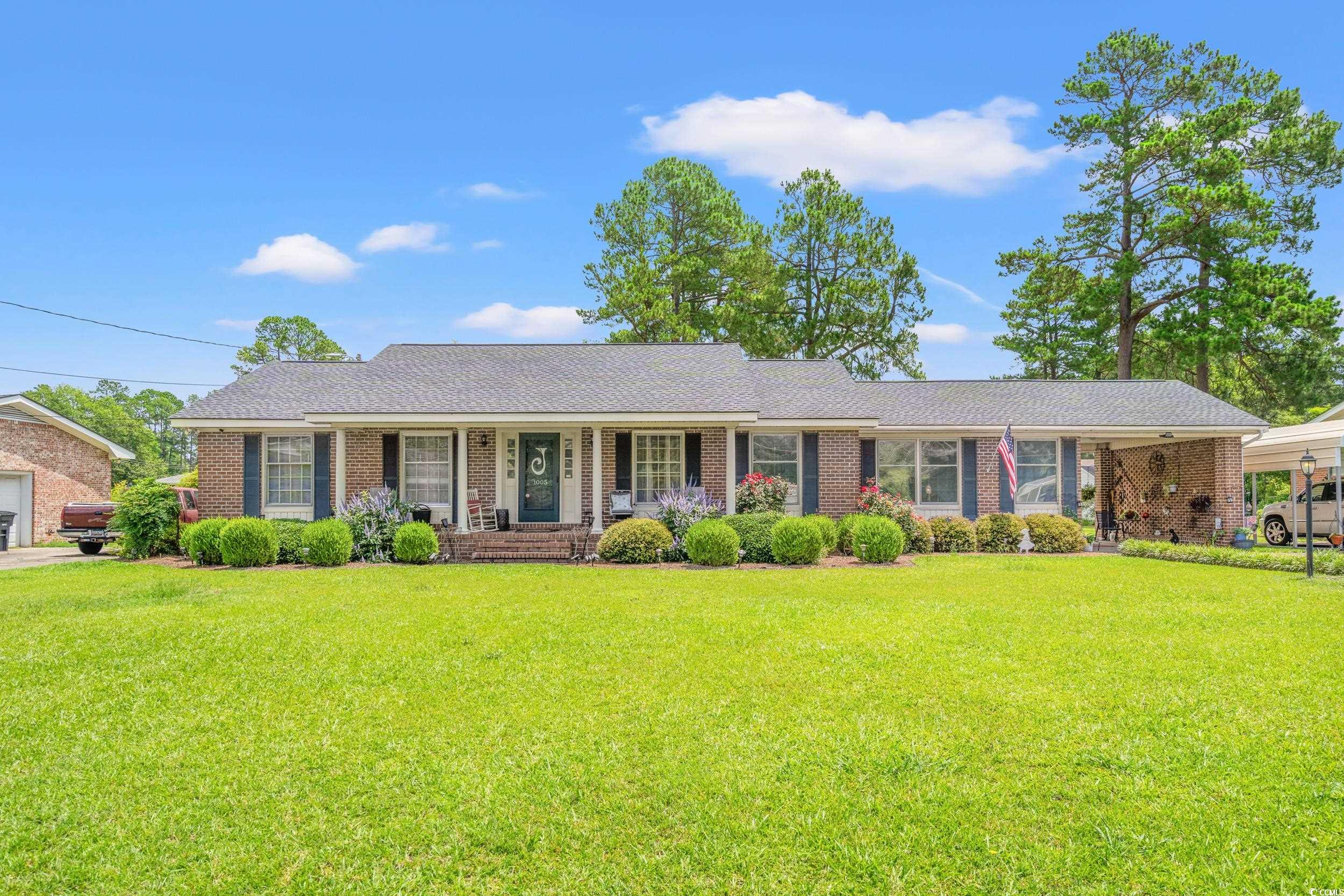 Ranch-style home featuring a porch, a front lawn, and brick siding