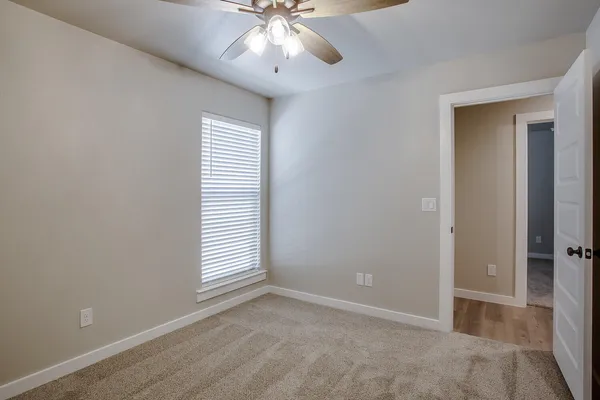 an empty room with windows and fan
