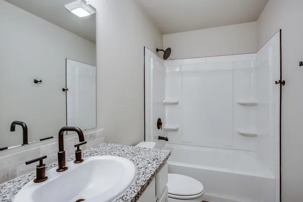a bathroom with a granite countertop sink toilet and shower