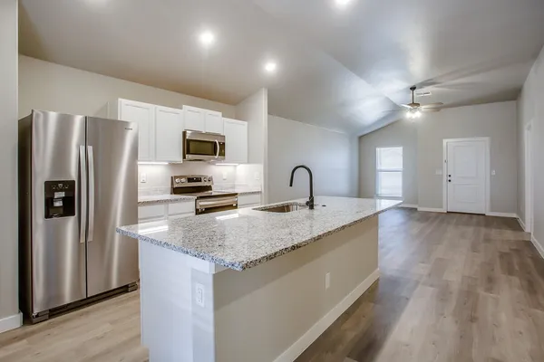 a kitchen with granite countertop a refrigerator and a sink