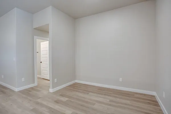 a view of an empty room with wooden floor and closet