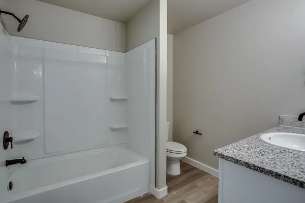 a bathroom with a granite countertop sink a toilet and bathtub