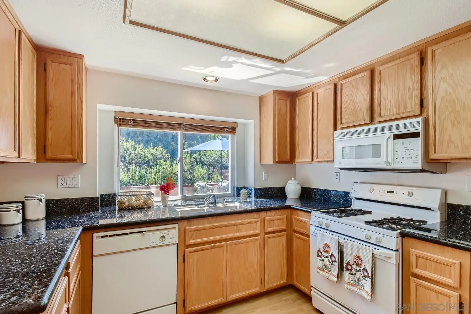 11756 Pickford Road San Diego, CA 92131 - Photo 7 of 26 a kitchen with stainless steel appliances granite countertop a stove a sink and a granite counter tops with wooden floors