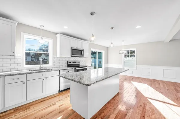 a large kitchen with stainless steel appliances granite countertop a sink dishwasher a stove and white countertops with wooden floor