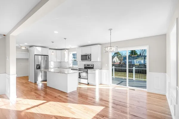 a open kitchen with stainless steel appliances granite countertop a refrigerator oven a sink dishwasher and white cabinets with wooden floor