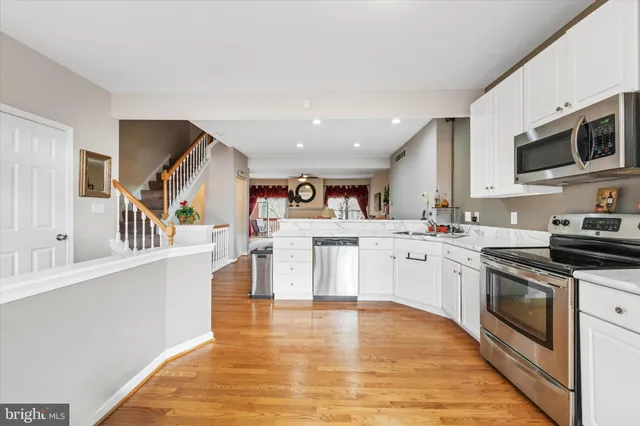 a large white kitchen with stainless steel appliances granite countertop a stove and a sink