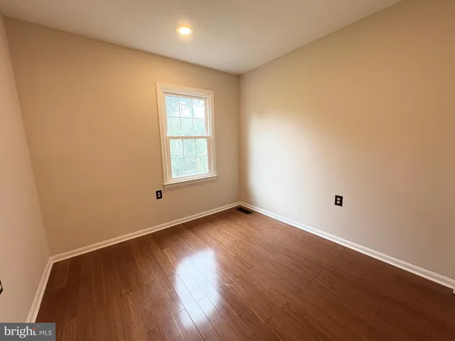 an empty room with wooden floor and a window