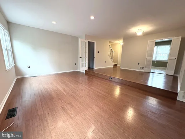 an empty room with wooden floor and windows