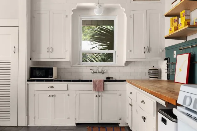 a kitchen with white cabinets and window