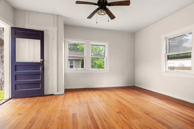 a view of empty room with wooden floor and fan
