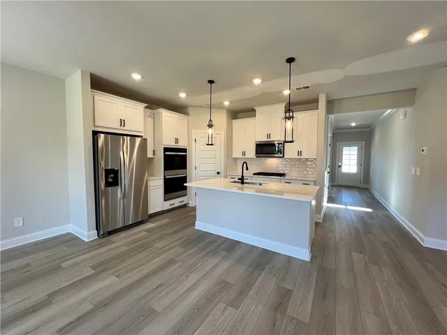 a view of kitchen with stainless steel appliances granite countertop a stove a refrigerator a sink and a oven with wooden floor