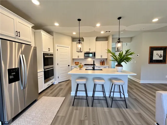 a kitchen with stainless steel appliances a dining table chairs stove refrigerator and cabinets