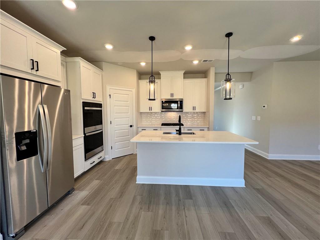 2969 Sweet Red Circle Braselton, GA 30517 - Photo 21 of 49 a view of kitchen with stainless steel appliances granite countertop a stove a refrigerator a sink and a oven with wooden floor