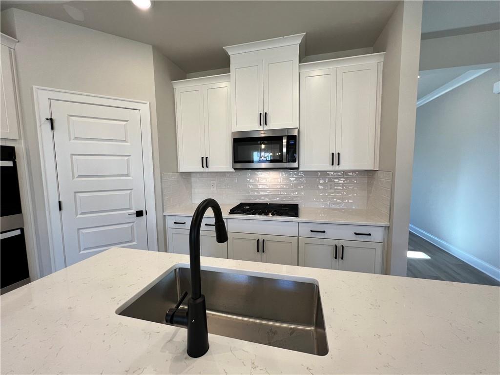 2969 Sweet Red Circle Braselton, GA 30517 - Photo 23 of 49 a kitchen with granite countertop a stove a sink and a microwave