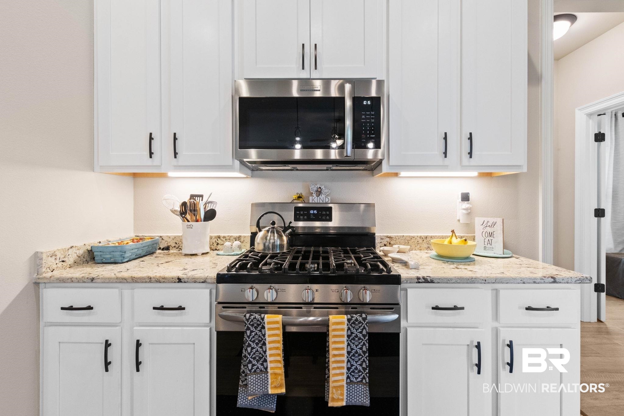 22244 Hibiscus Circle Foley, AL 36535 - Photo 22 of 51 Contemporary kitchen featuring white shaker cabinetry, granite countertops, and stainless steel appliances including a gas range and built-in microwave
