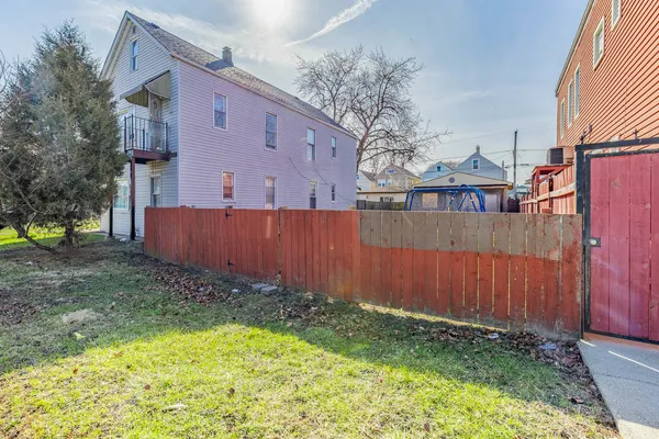 a view of a backyard with a fence and a large tree