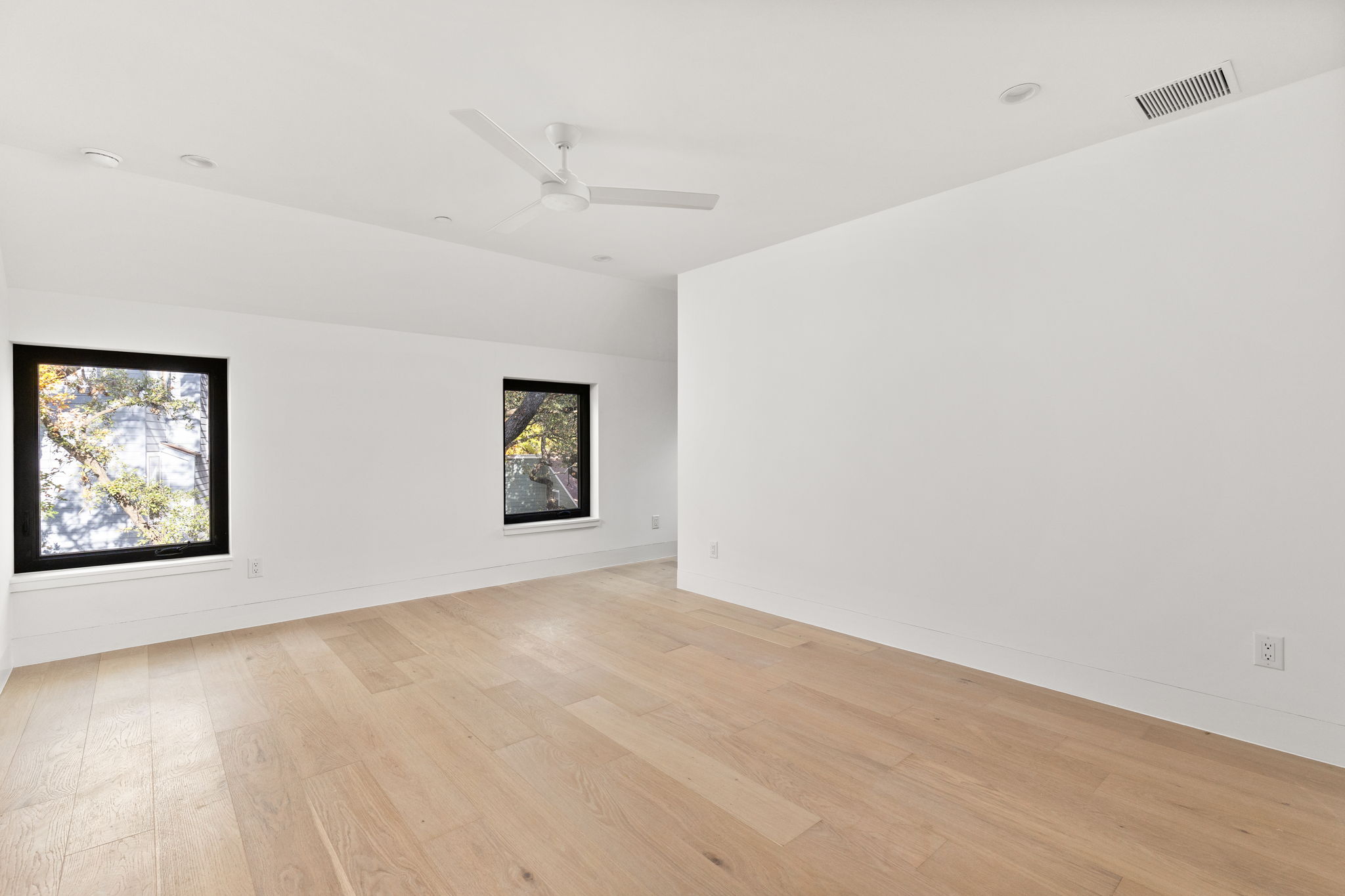 1603 Chelsea Lane, Unit 3 Austin, TX 78704 - Photo 25 of 40 an empty room with wooden floor ceiling fan and windows