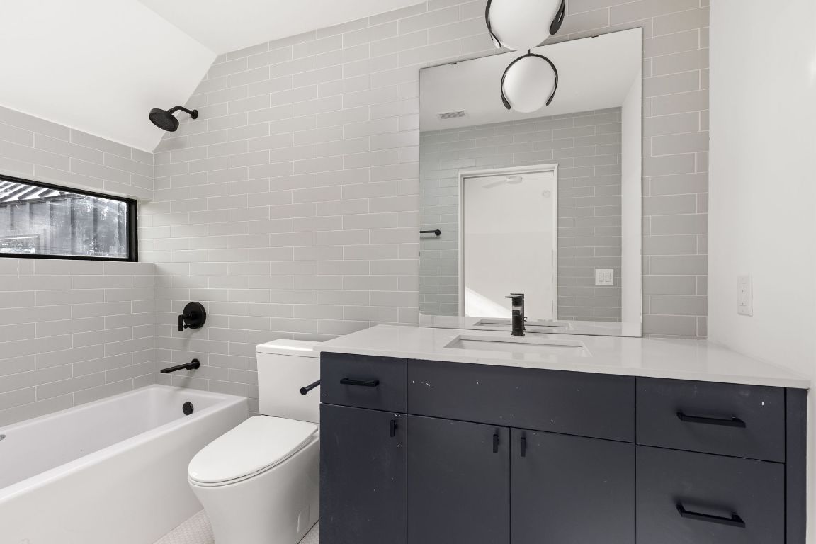 1603 Chelsea Lane, Unit 3 Austin, TX 78704 - Photo 28 of 40 Full bath featuring shower / bath combination, vanity, tile walls, and vaulted ceiling