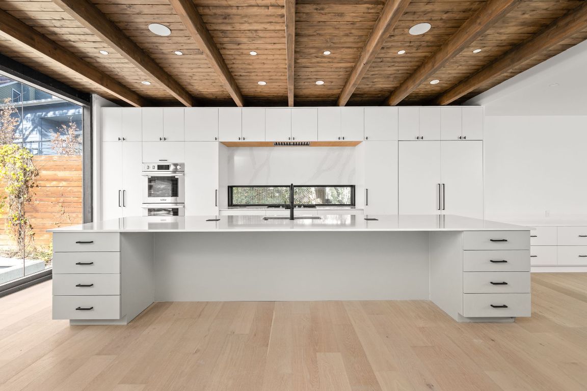 1603 Chelsea Lane, Unit 3 Austin, TX 78704 - Photo 4 of 40 Kitchen with a wood ceiling with exposed beams, light wood finished floors, white cabinetry, a spacious island, and modern cabinets